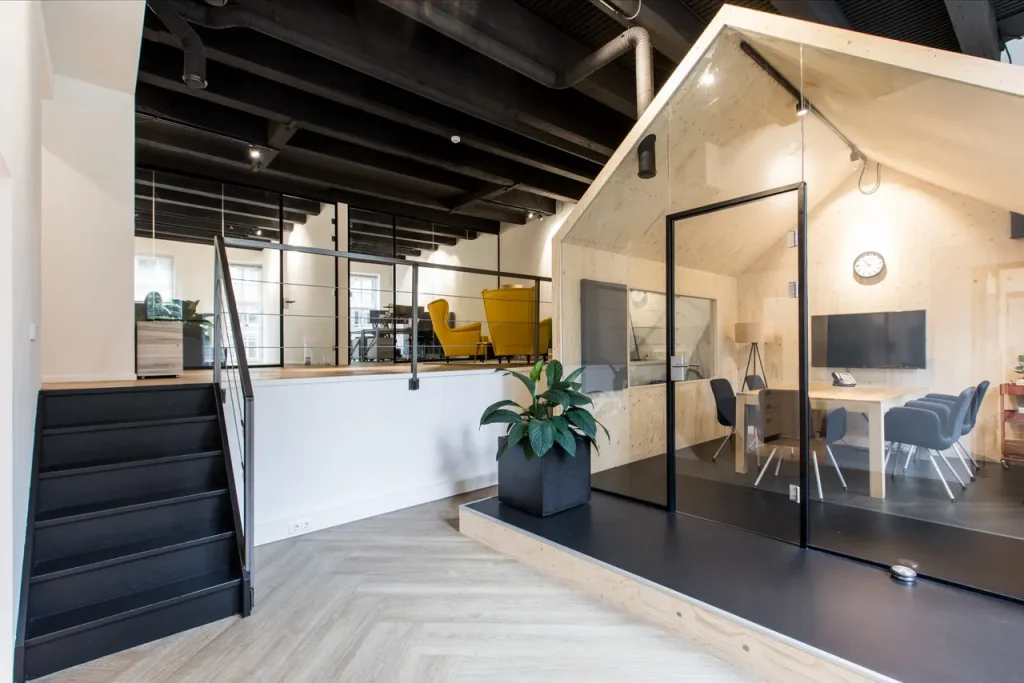 Het kantoor van gevoelszaken. Blokhut, vergadertafel, klok. Kleuren: wit, hout, antraciet.